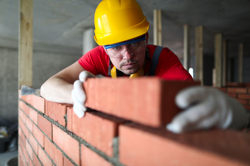ouvrier qui pose une brique sur un mur
